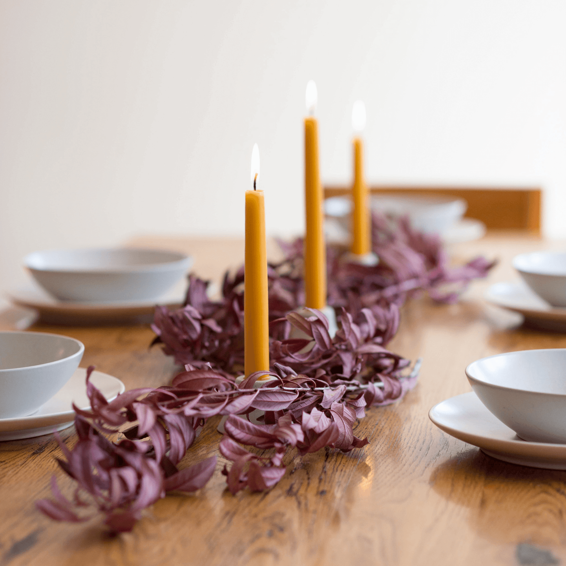 Pure beeswax taper candles from Bluecorn Candles on a bright, clean dinner table.