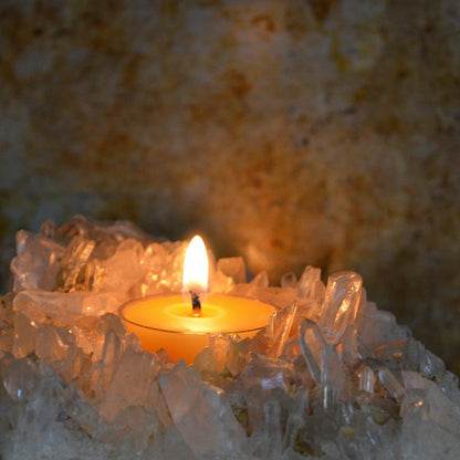 Bluecorn Beeswax Raw Tea Light burning inside of a crystal tea lights holder. Wax is golden in color and shows through the clear cup that it is in. 